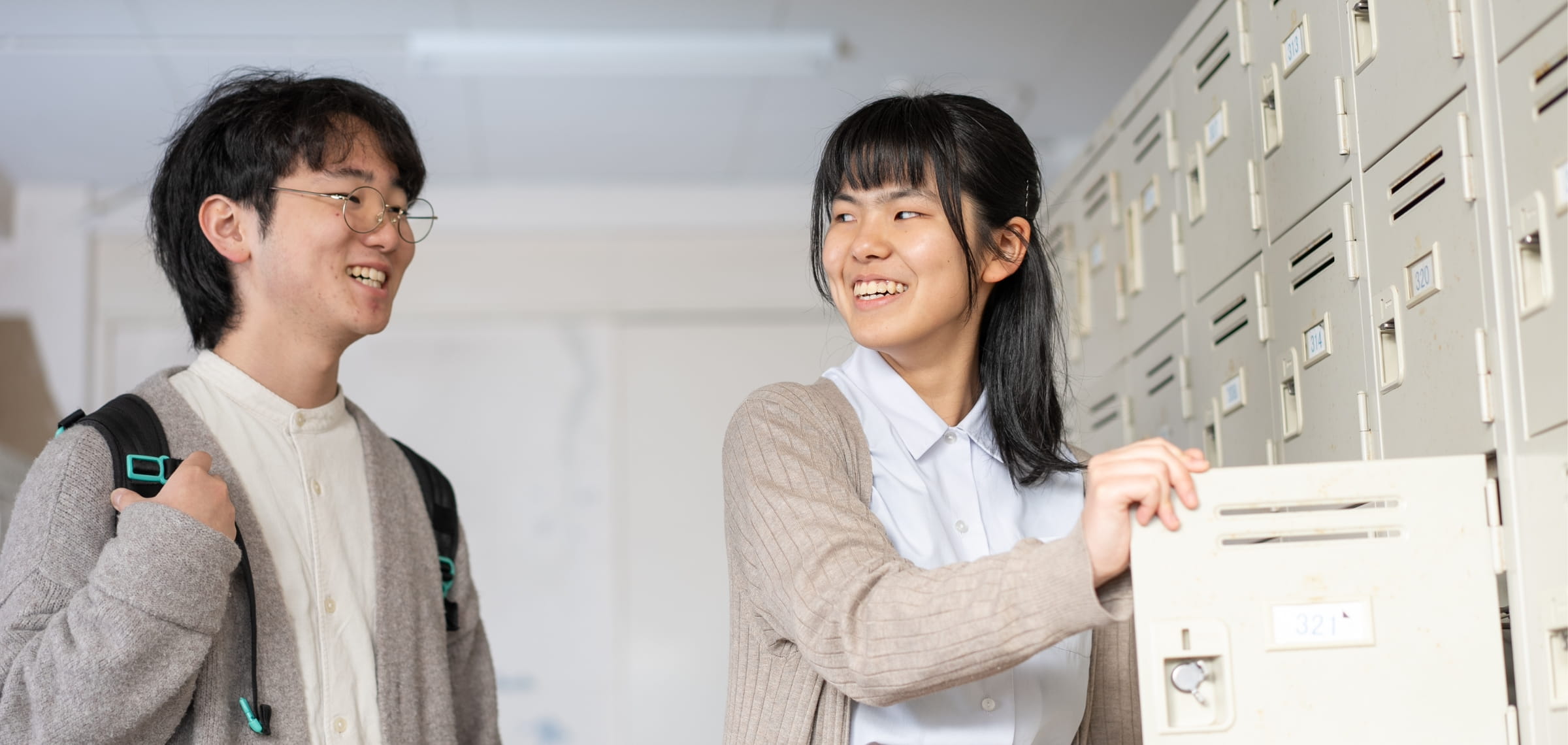 男子学生と女子学生がロッカーの前で親しげに会話する様子